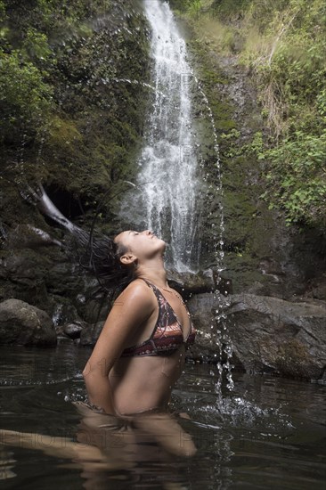 Caucasian woman tossing hair under waterfall