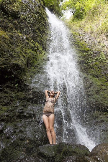 Caucasian woman standing on rock near waterfall