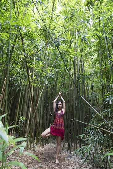 Caucasian woman standing in bamboo forest performing yoga