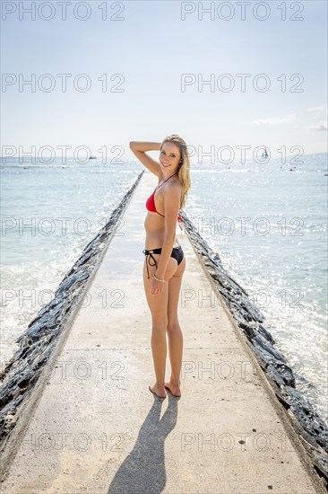 Caucasian woman wearing bikini standing on breakwall