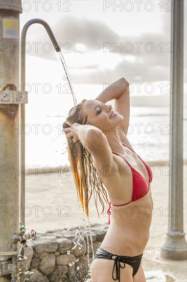 Caucasian woman wearing bikini under outdoor shower