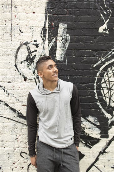 Smiling Mixed Race man standing near mural on wall