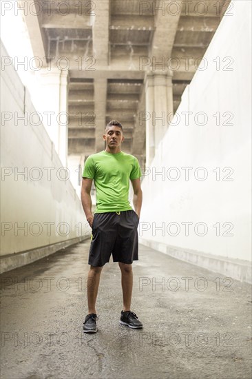 Serious Mixed Race man standing under bridge