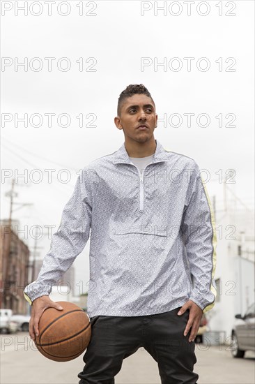 Portrait of curious Mixed Race man holding basketball