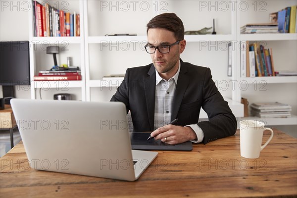 Caucasian businessman using laptop and digital tablet in office