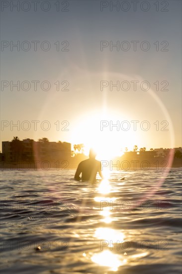 Caucasian man sitting on surfboard in ocean