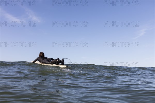 Caucasian man paddling on surfboard