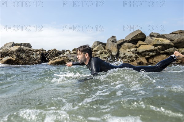 Caucasian man paddling on surfboard