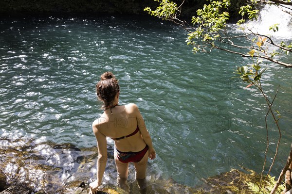 Caucasian woman wading in pool near waterfall
