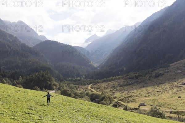 Distant carefree person walking on hill near mountains