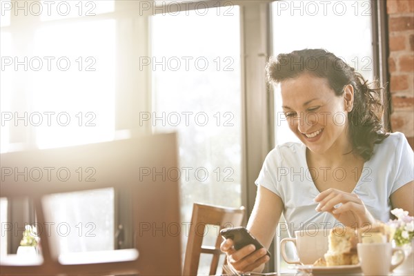 Hispanic woman in cafe using cell phone