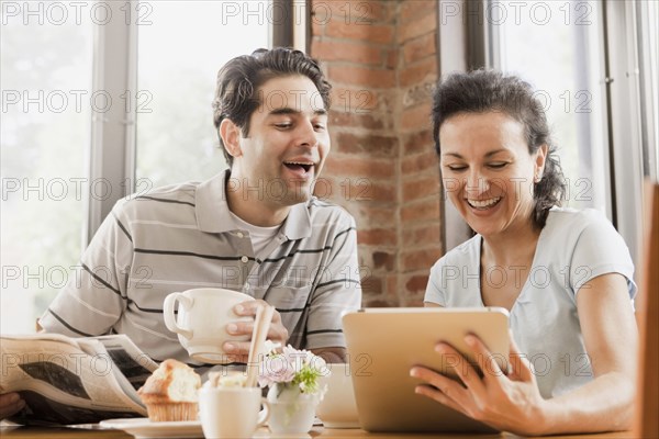 Hispanic couple using digital tablet in cafe