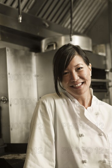 Smiling Chinese chef standing in commercial kitchen