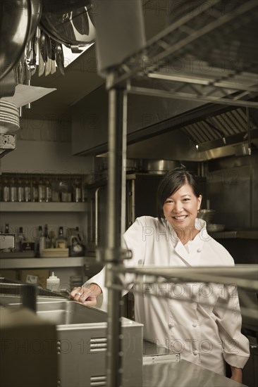 Smiling Chinese chef standing in commercial kitchen