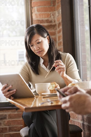 Chinese woman using digital tablet in cafe