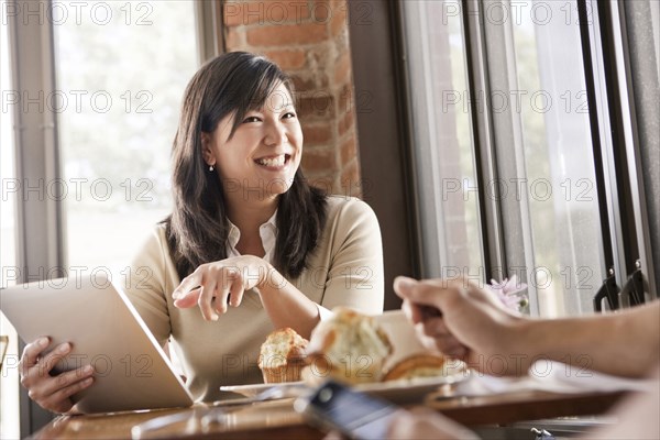 Chinese woman using digital tablet in cafe