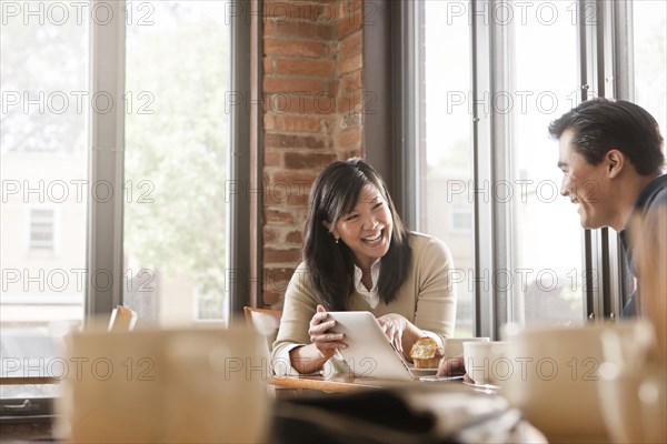 Chinese woman digital tablet to husband in cafe