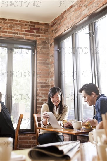 Chinese woman digital tablet to husband in cafe