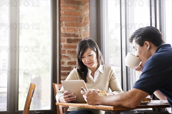 Chinese woman digital tablet to husband in cafe