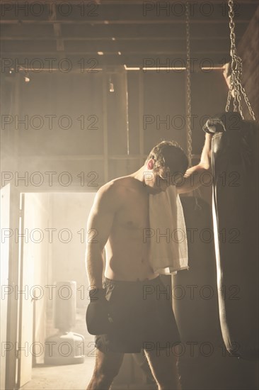Fatigued boxer leaning on punching bag
