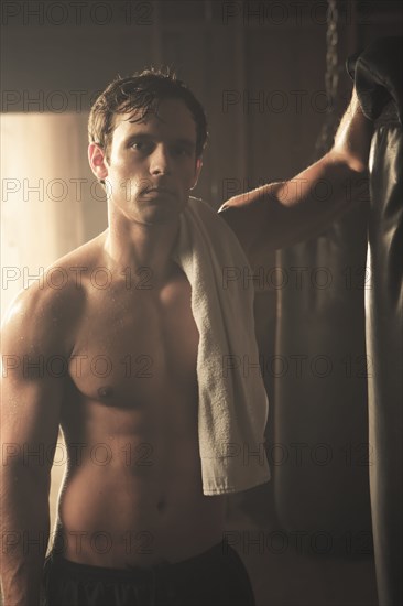 Fatigued boxer leaning on punching bag