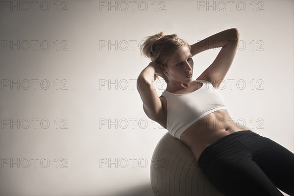 Caucasian woman doing sit-ups on exercise ball