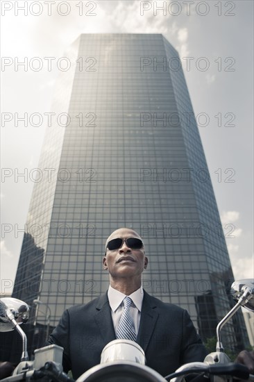 Black businessman riding motorcycle in city