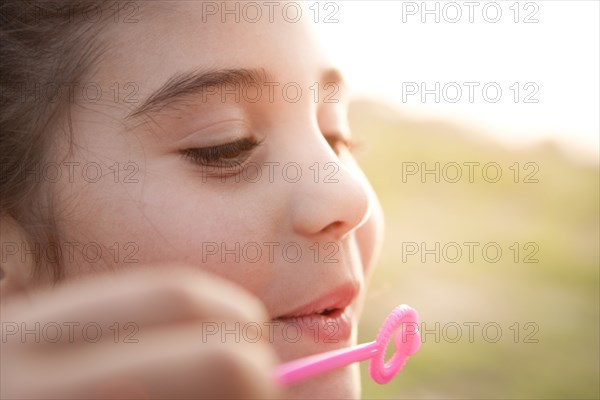 Mixed race girl blowing bubbles