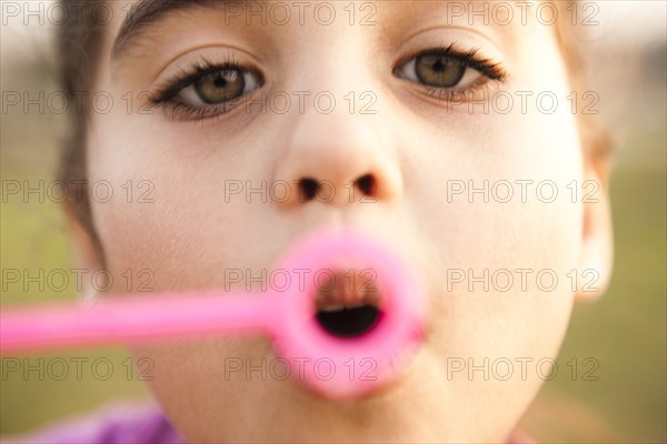 Mixed race girl blowing bubbles