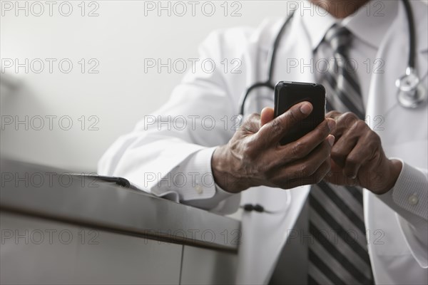 African American doctor text messaging on cell phone