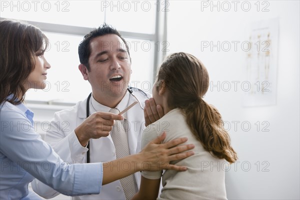 Doctor examining patient while mother watches