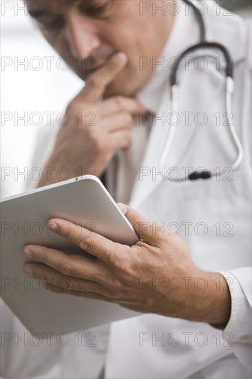 Mixed race doctor using digital tablet