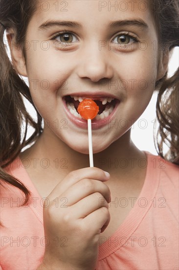Mixed race girl eating lollipop