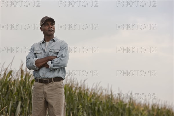 African American man standing in field with arms crossed