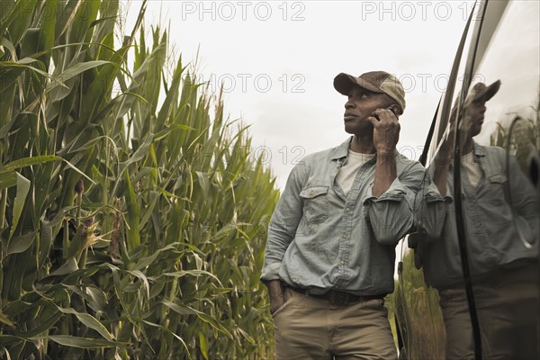 African American farmer talking on cell phone in field