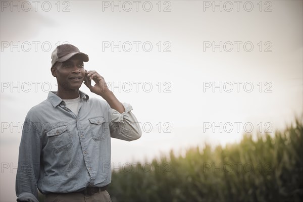 African American farmer talking on cell phone in field