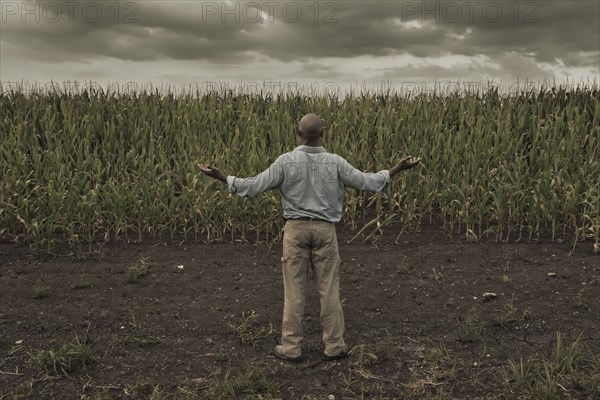 African American farmer standing in field with arms outstretched