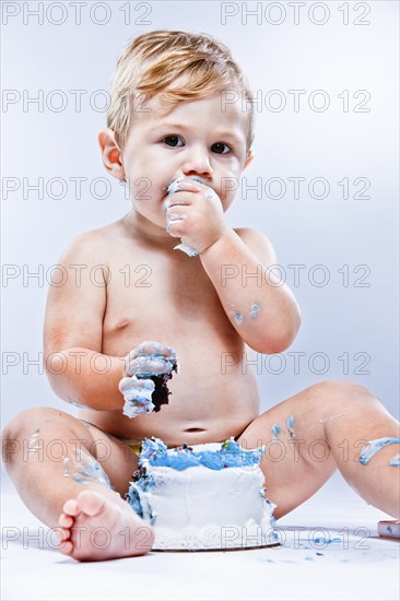 Caucasian baby eating birthday cake