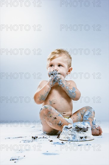 Caucasian baby eating birthday cake