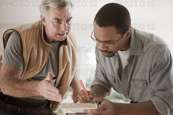 Man talking to carpenter measuring lumber