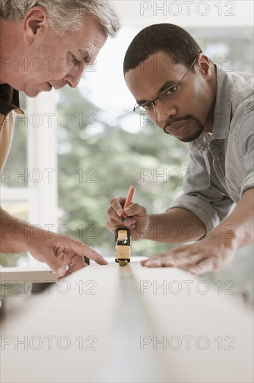 Man watching carpenter measuring lumber