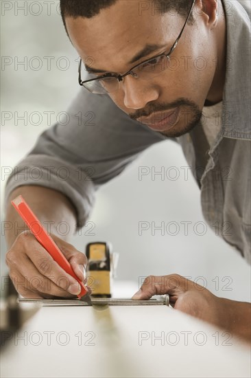 Black carpenter measuring lumber