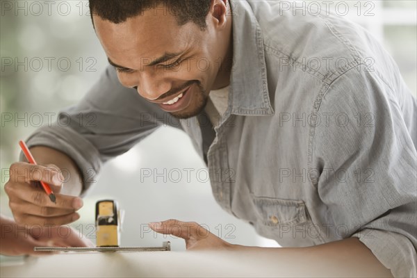 Black carpenter measuring lumber