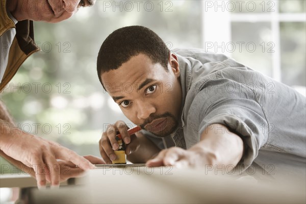 Black carpenter measuring lumber