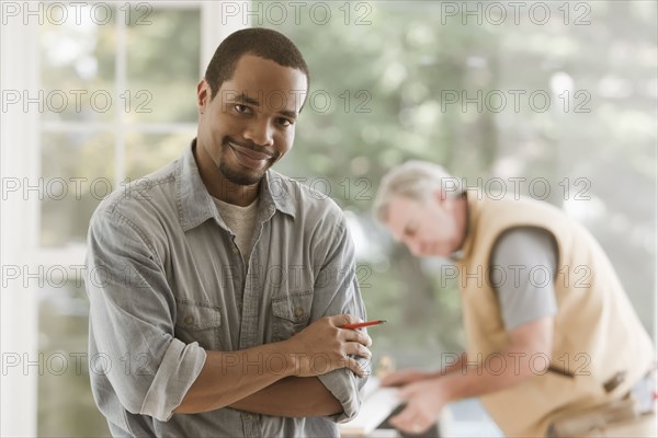 Black carpenter standing with arms crossed