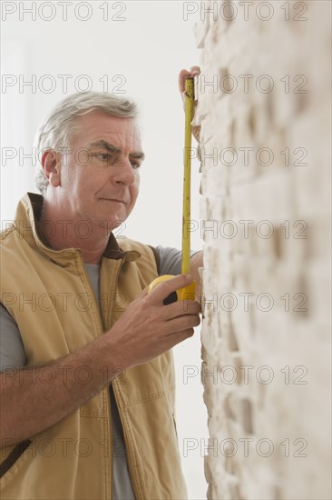 Caucasian carpenter measuring wall