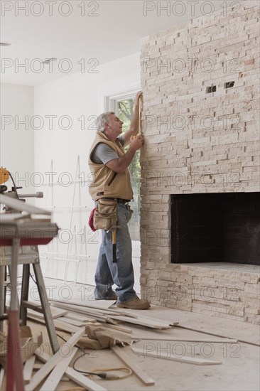 Caucasian carpenter measuring fireplace