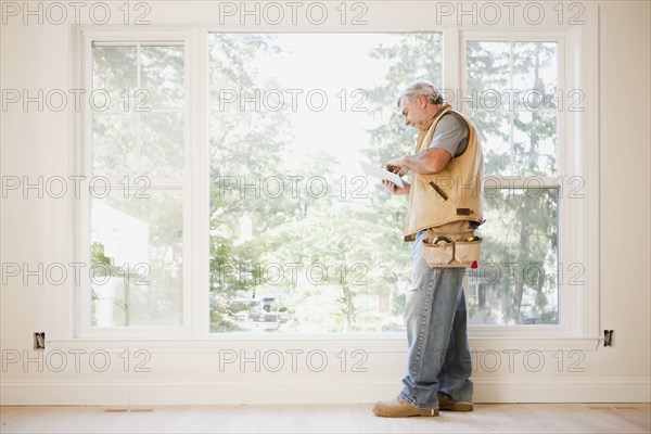 Caucasian carpenter using digital tablet in empty room
