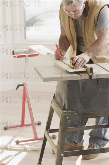 Caucasian carpenter measuring lumber
