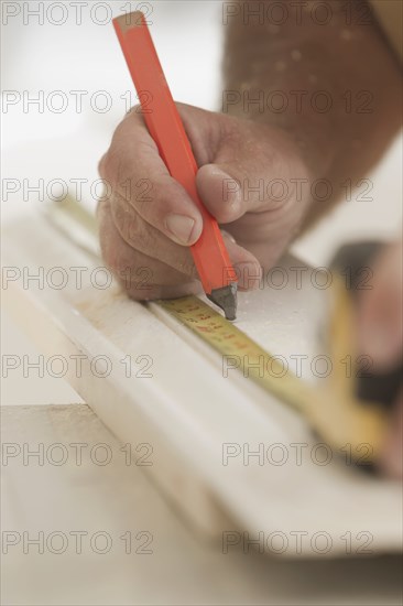 Caucasian carpenter measuring lumber